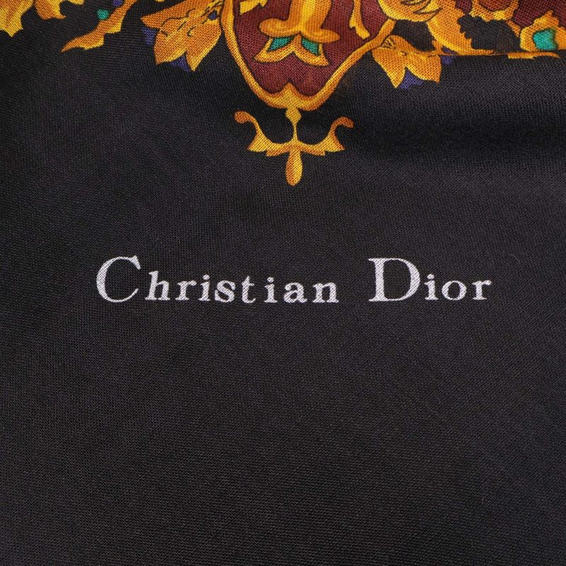 Närbild på vit broderad Christian Dior-text på svart tyg