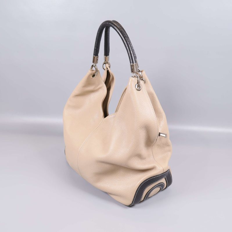 Snedvy på beige väska med mörkt handtag och dekorativ botten