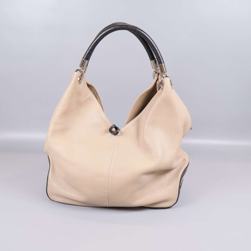 Framsidan av beige axelväska med mörkt handtag