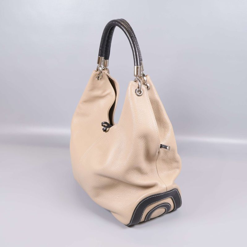 Beige axelväska med mörkt handtag och mönstrad botten