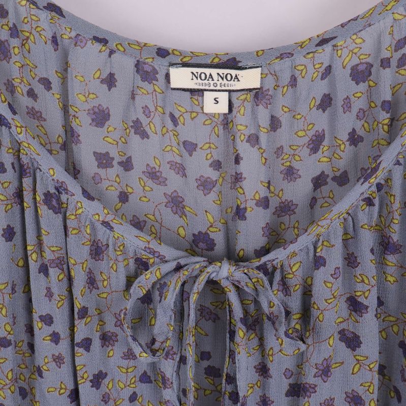 Närbild på blommig blus med etikett och snörning