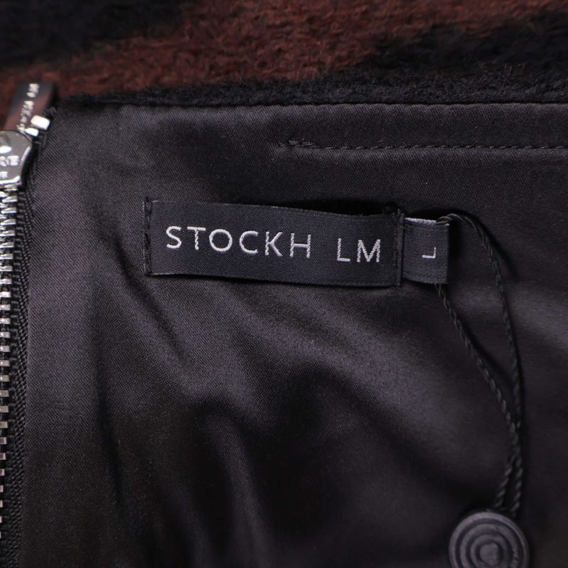 Närbild på svart etikett med texten STOCKH LM i kjol