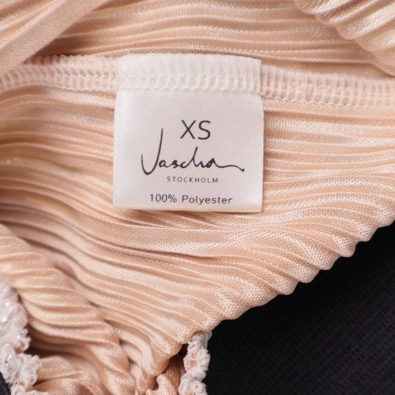 Materialetikett som visar 100% polyester och storlek XS
