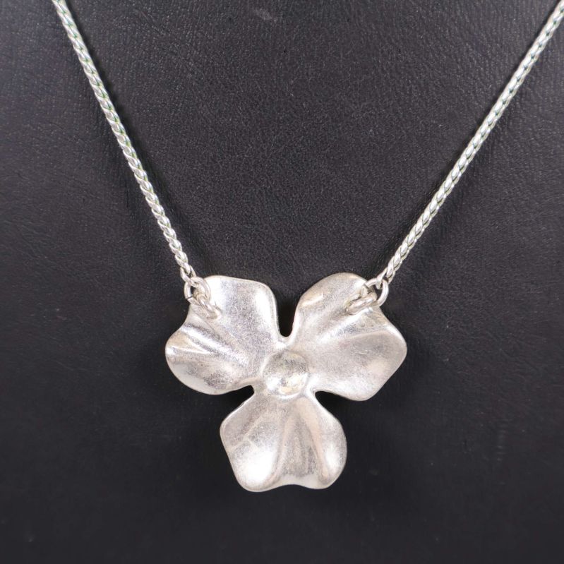 Baksidan av blomformad berlock i matt silver