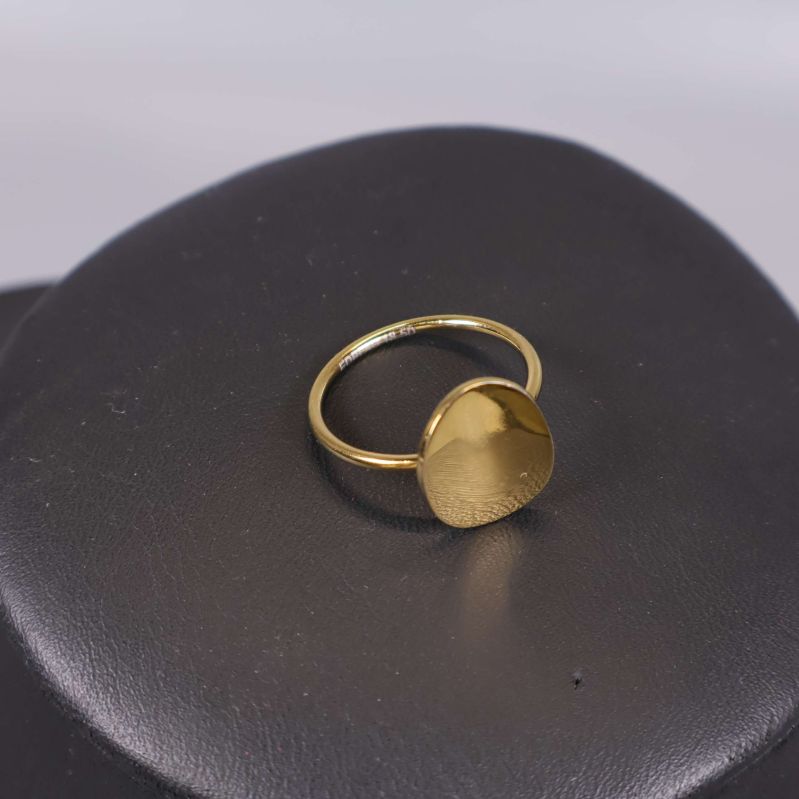 Guldfärgad ring placerad på svart underlag i närbild