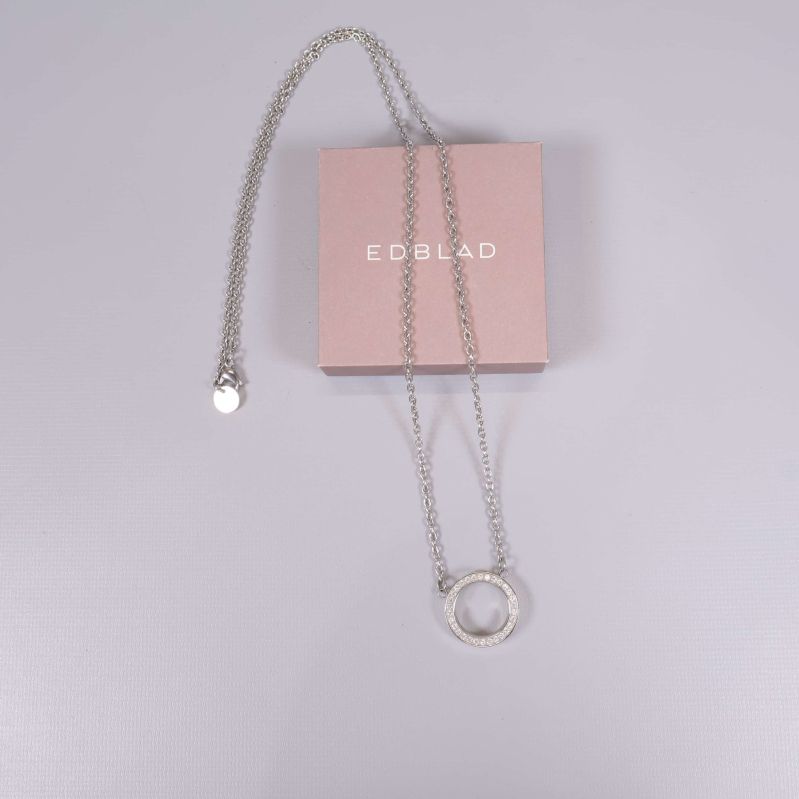 Halsband med cirkelformat hänge placerat på rosa ask