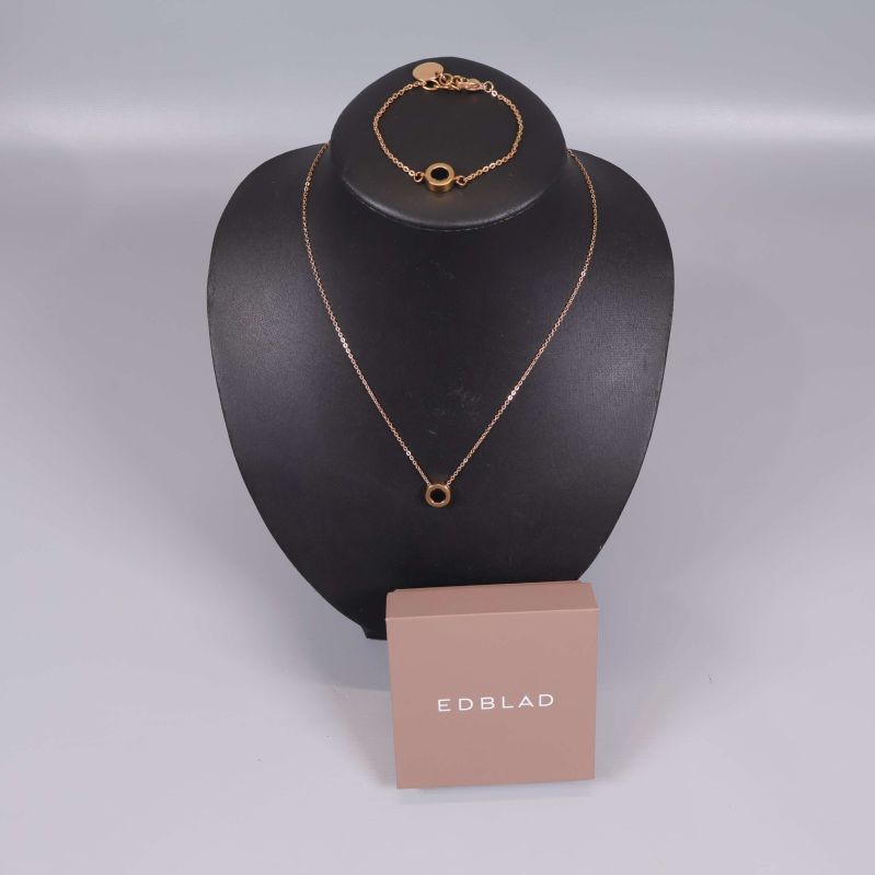 Smyckesset med halsband och armband i guld med cirkelmotiv på stativ och ask