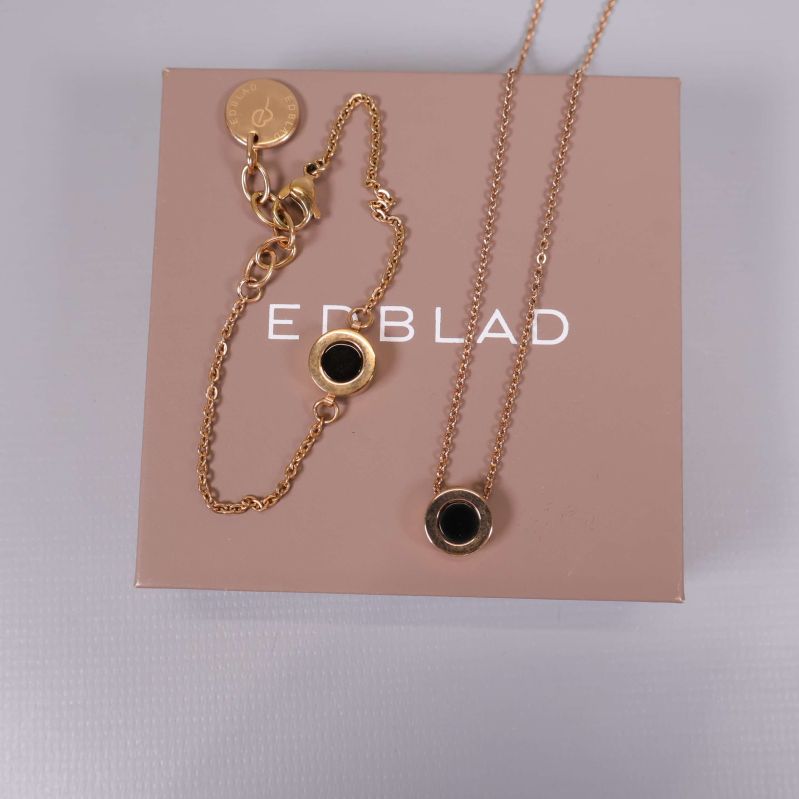 Armband och halsband med guldkedja och svart cirkel på Edblad-låda