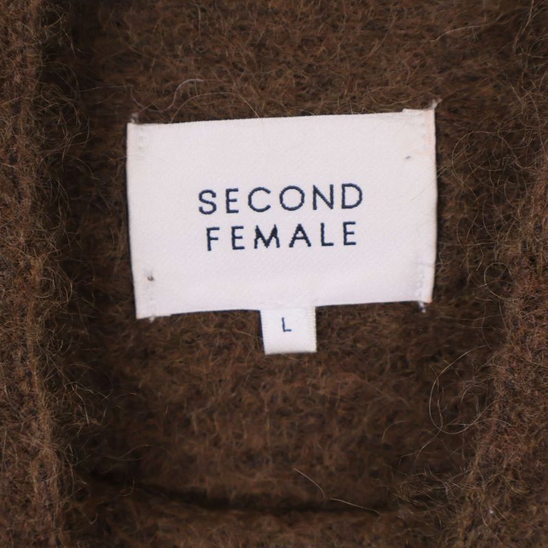Närbild av vit etikett med Second Female logga i tröjans krage