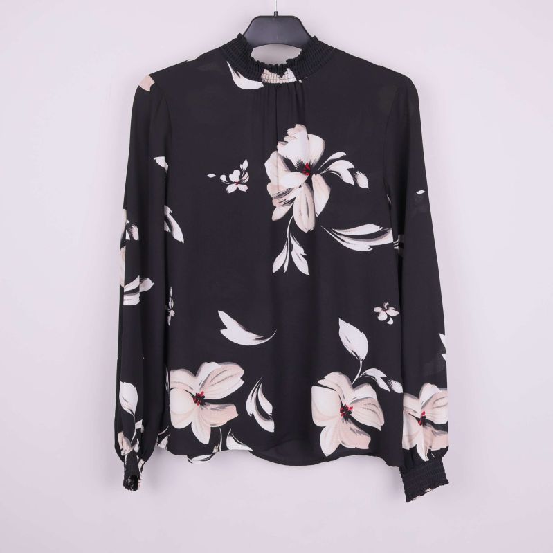 Svart blus med stort blommönster på galge framifrån
