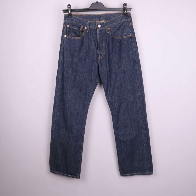 Framsida av mörkblå raka jeans upphängda mot ljus bakgrund