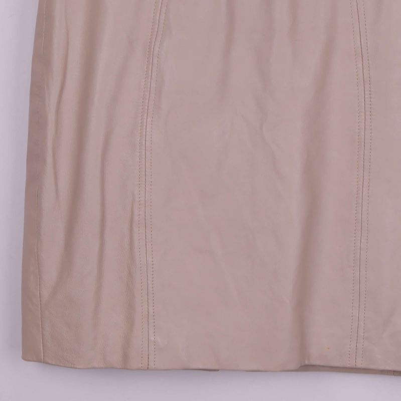 Närbild på nedre del av beige läderkjol