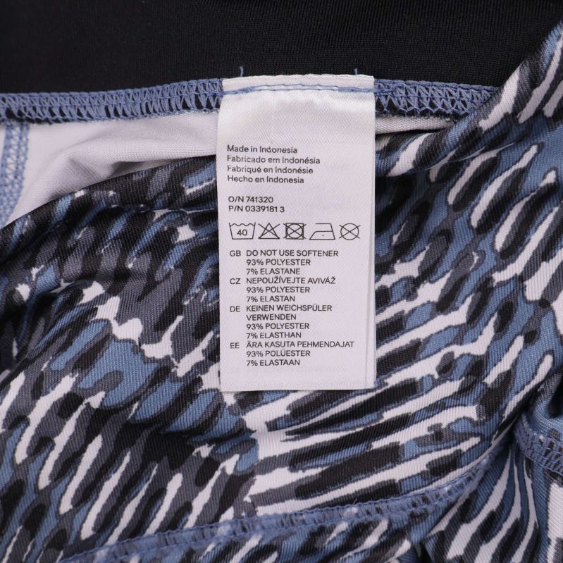 Materialetikett visar komposition: 87% polyester, 13% elastan