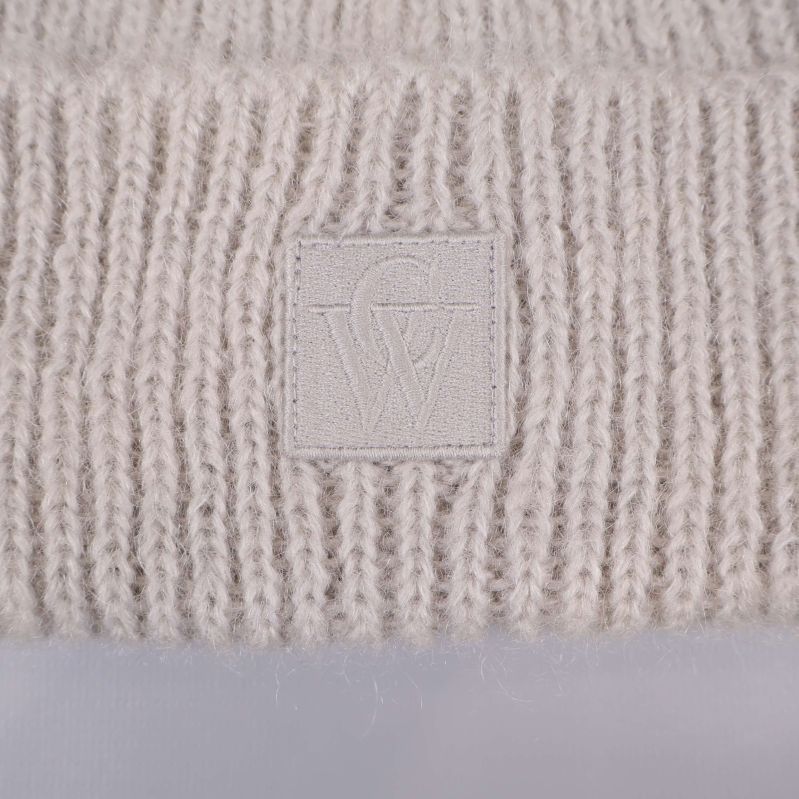 Närbild på broderad CW-logga på mössans kant