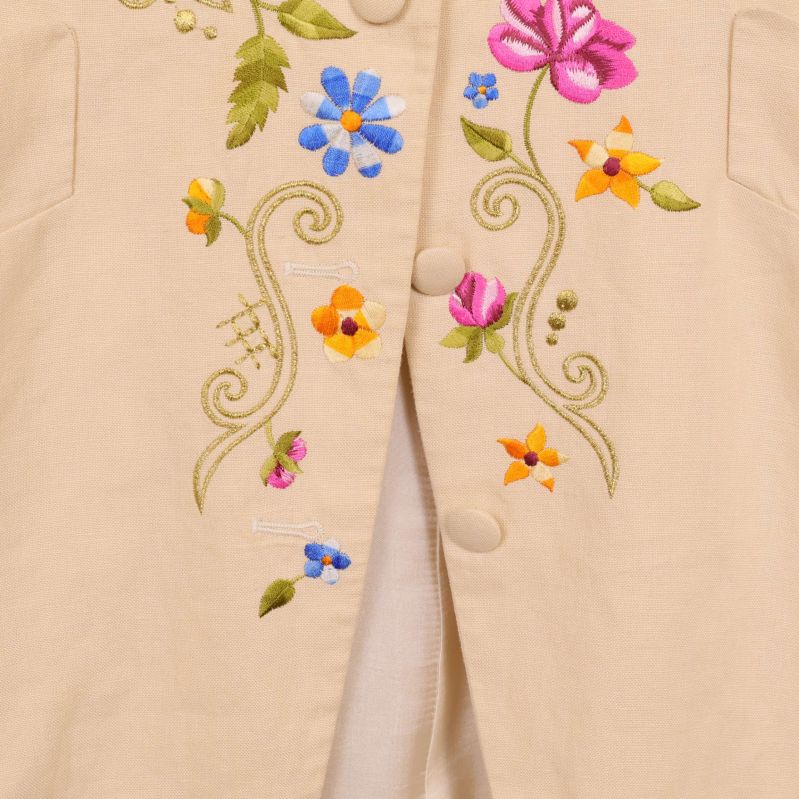 Närbild på broderade blommor och knapphål framtill