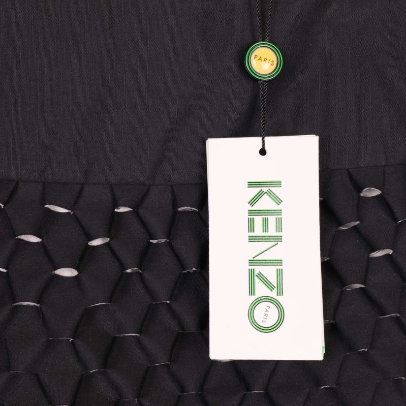 Närbild på Kenzo-tag fäst vid svart kjol med grafiskt mönster