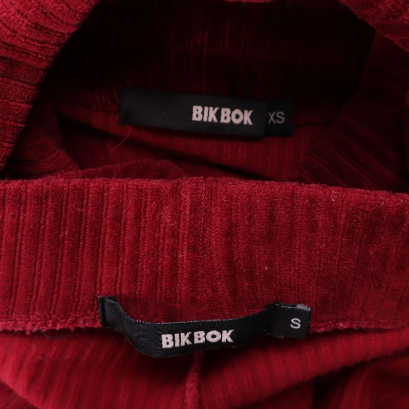 Närbild på BIK BOK-etikett i ribbat vinrött tyg