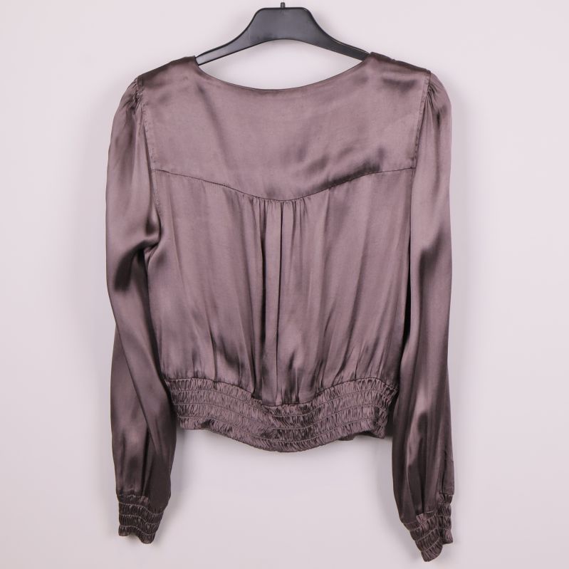 Baksida av glansig blus med smock nertill