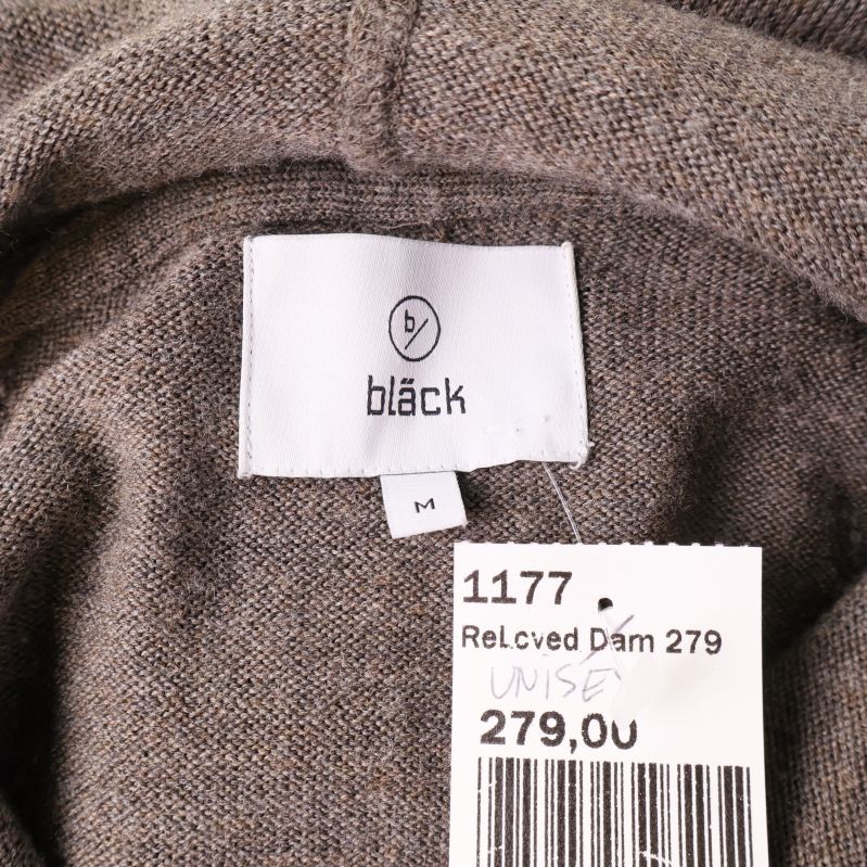 Närbild på vit etikett med varumärket Bläck och storlek M