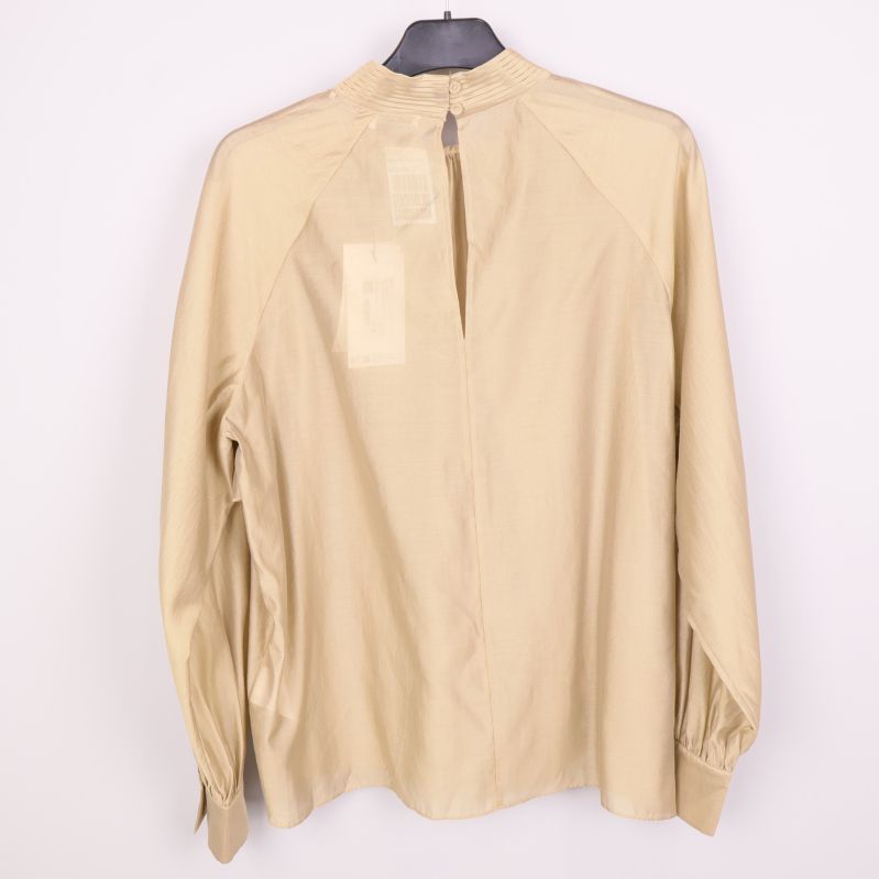 Baksidan av beige blus med knappslå
