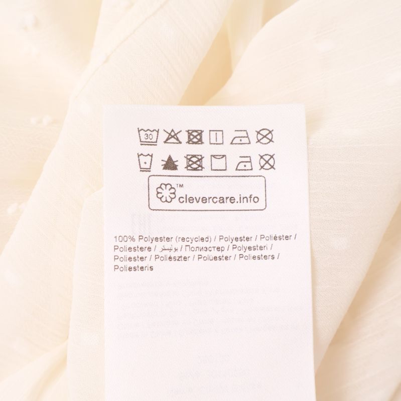 Materiallapp med text 100% polyester på blus