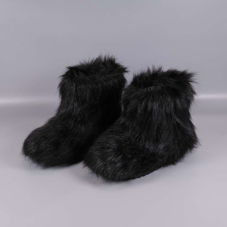 Ett par svarta boots med lång fuskpäls på grå bakgrund