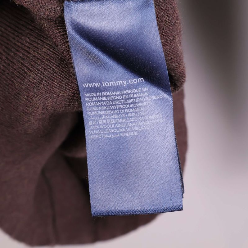Blå tvättetikett med Tommy Hilfiger-information på brun tröja