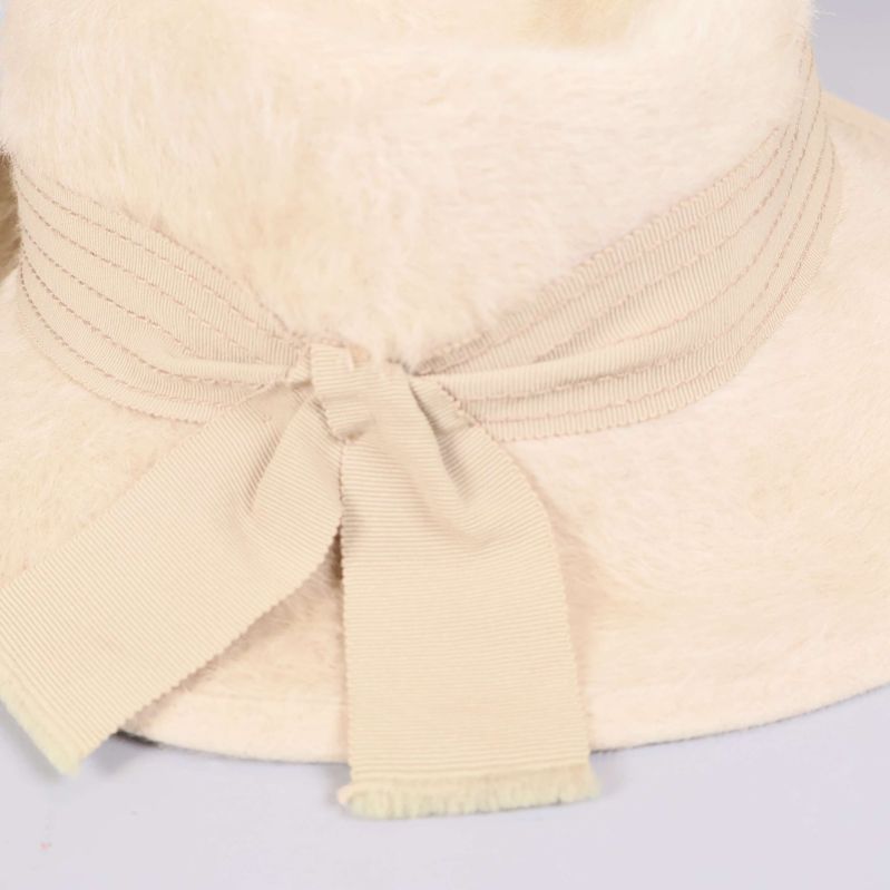 Närbild på krämvit rosett och sydd hattkant i textil
