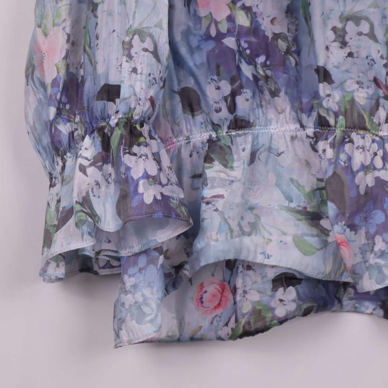 Volangdetalj nertill på blommig blus