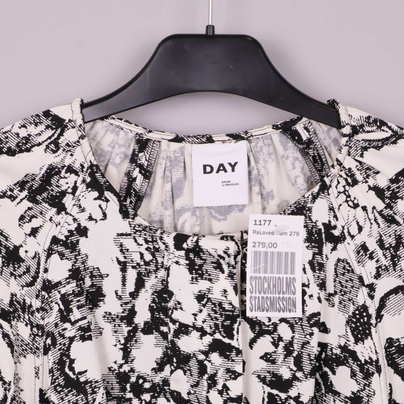 Närbild av blusens övre del med Day-etikett